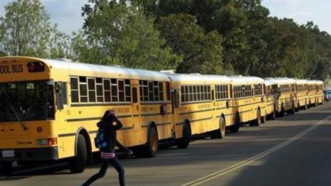 student-runs-across-street-in-front-of-busses